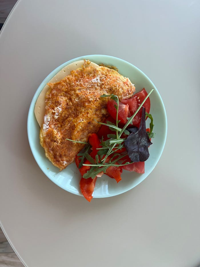 Savory omelette served with a fresh tomato and mixed greens salad on a light plate.